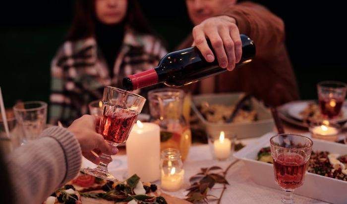 Wine is poured into a glass over a full dinner table